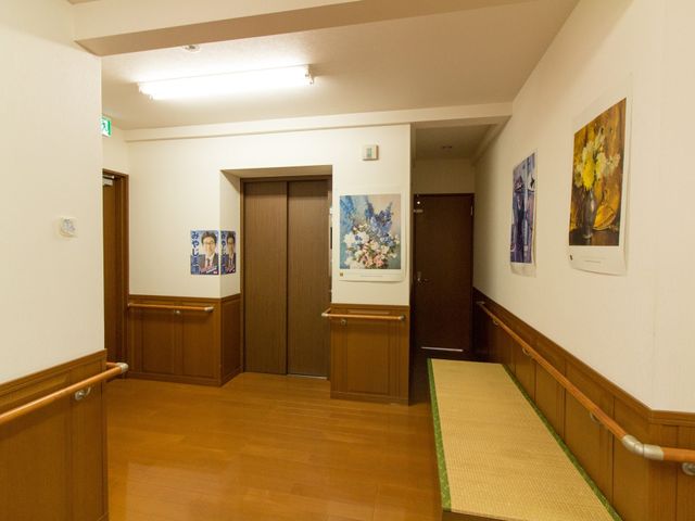清潔で落ち着いた廊下 エレベーター 温かみのある照明とアートが飾られた静かな廊下です。ゆったりとした空間で働く安らぎを感じられます。