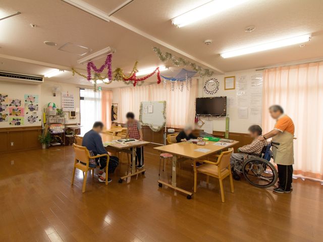 明るい多目的室の風景 共有スペース 活動的な雰囲気のある多目的室です。スタッフが利用者の方と共に楽しい時間を過ごしており、和やかな交流の場となっています。