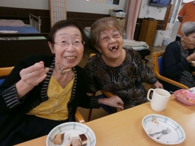 笑顔の高齢者と食事 入居者様の笑顔 心温まる食事の時間を提供しており、ご入居者が明るい笑顔で楽しんでいます。スタッフとして笑顔あふれる環境で働きませんか。