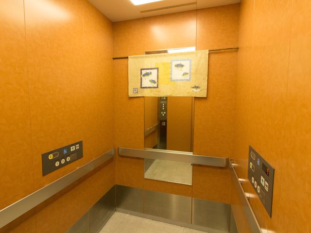 暖色調のエレベーター内部 エレベーター 落ち着いた色合いのエレベーター内で、訪れる方々が快適に移動できる空間が整っています。
