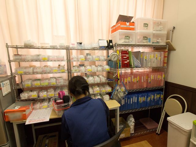 薬品整理をする職員 スタッフルーム 配薬準備に集中する職員がいる快適な作業スペースです。日々の健康管理もサポートする充実した設備が整っています。