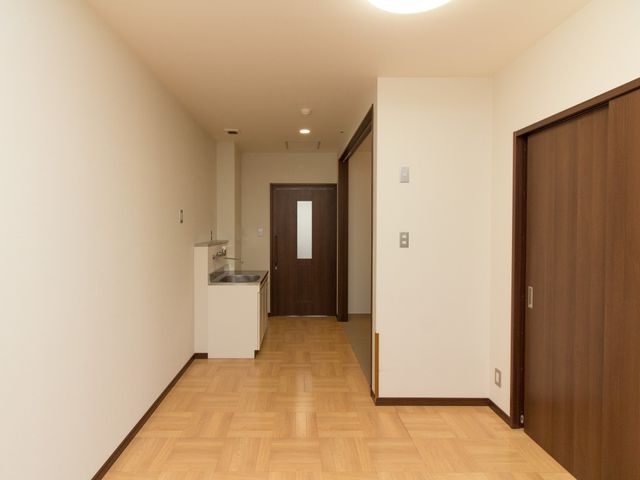 洋室の入り口と洗面所 居室 広々とした居室の一角には、洗面台も備え付けられており、日々の快適な生活をサポートします。明るく落ち着いた色合いが心地よい空間を演出しています。