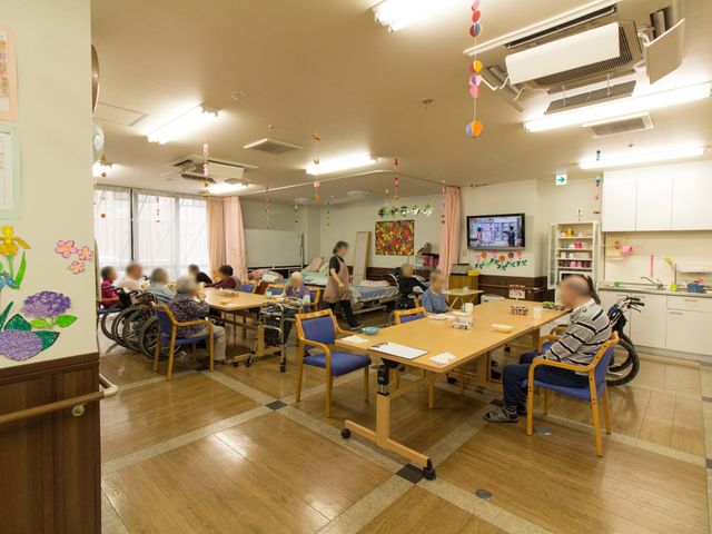 活気ある共有スペース 共有スペース 光が差し込む広々とした食堂では、利用者が集い、さまざまな活動を楽しんでいる様子です。ゆとりを持った配置のテーブルや椅子が配置され、落ち着いた雰囲気が演出されています。