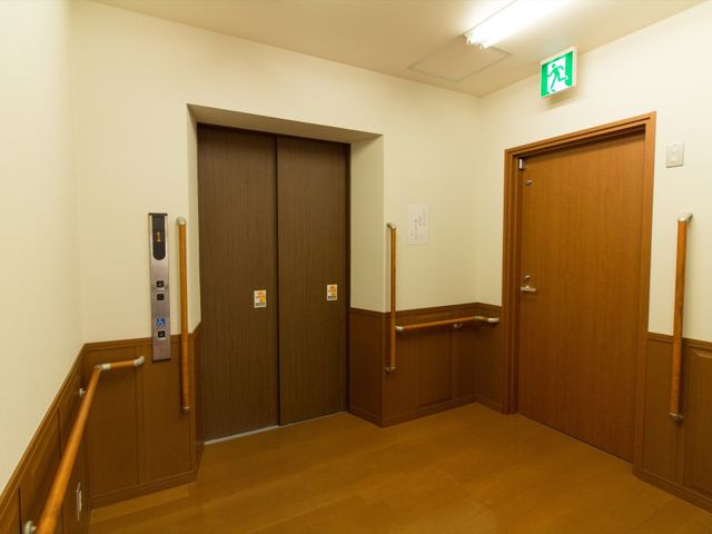 廊下のエレベーターと扉 エレベーター 手すりが整備された廊下です。移動のしやすさを考慮し、安全で快適な環境が提供されています。