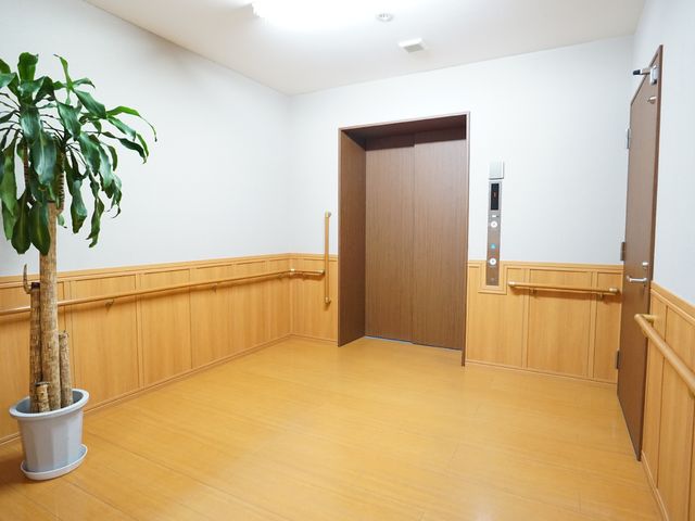 床と壁が木目調の廊下 エレベーター ゆったりとしたスペースが確保された廊下です。安全に考慮して手すりが設置されており、快適にお過ごしいただけます。