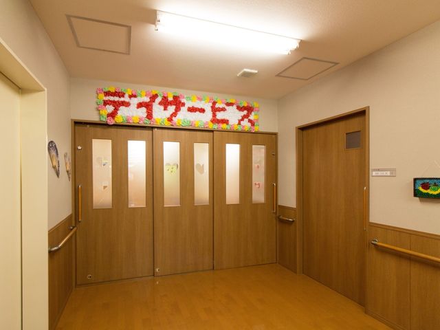 廊下の装飾付き出入口 デイサービス カラフルな装飾が施された廊下は、心温まる雰囲気です。ゆったりとした空間で働きやすさも見込めます。