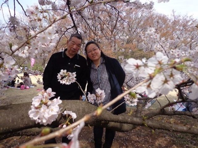 桜と笑顔の二人 お花見 ゆったりとした中庭で、利用者様が桜の木の下で温かい笑顔を見せています。共に季節の移ろいを感じながら、安らぎの時間をお過ごしいただける環境です。