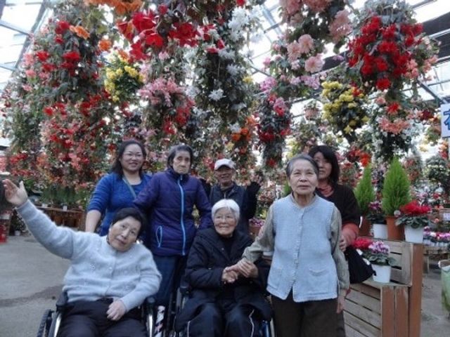 花に囲まれた人々 花園 色とりどりの花々が咲き誇る庭で、利用者とスタッフが楽しそうに過ごしています。心温まる光景は、日々の憩いの場を提供してくれます。