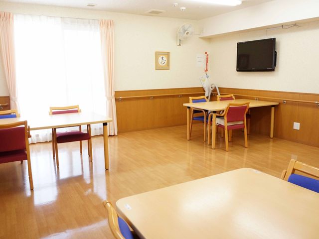明るいダイニングルーム 食堂 天井には照明が明るく、ダイニングテーブルが配置された快適な食空間です。壁にはテレビがあり、共同の食事時間を楽しめます。