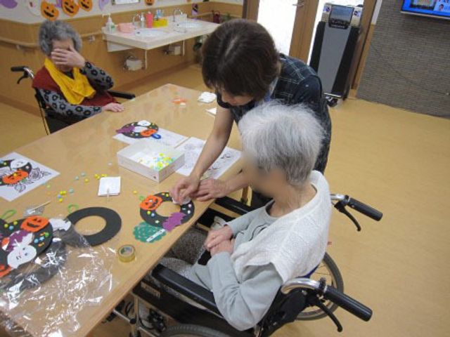 手作業を行う活動室 レクリエーション 明るい多目的室で、職員が利用者様と共に手作業を行っており、和やかな雰囲気が感じられます。創造性を育むこの空間で、一緒に楽しみながら支援をしませんか。