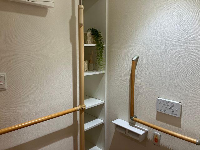 廊下の手すりと棚 トイレ前の収納 廊下に設けられた手すりが移動をサポートし、収納棚では小物を整理できます。安全で機能的な設計が考慮された空間です。