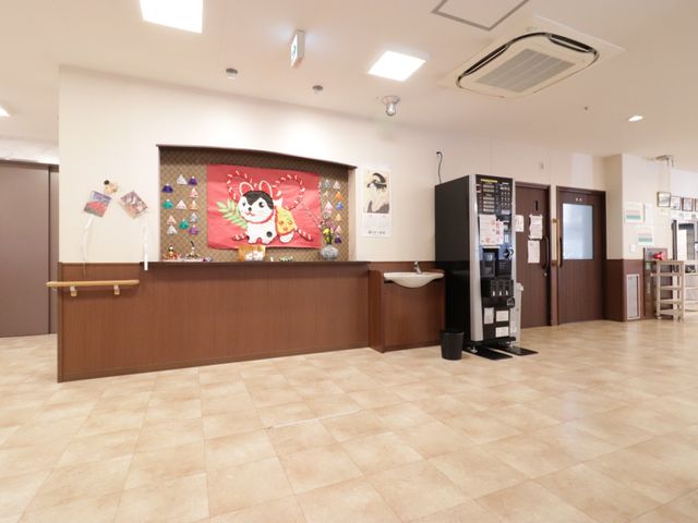 明るい受付と自動販売機 ホール 受付付近は、温かみのある照明と清潔感のあふれる床で迎えてくれます。自動販売機も設置され、待合時間も快適に過ごせそうです。