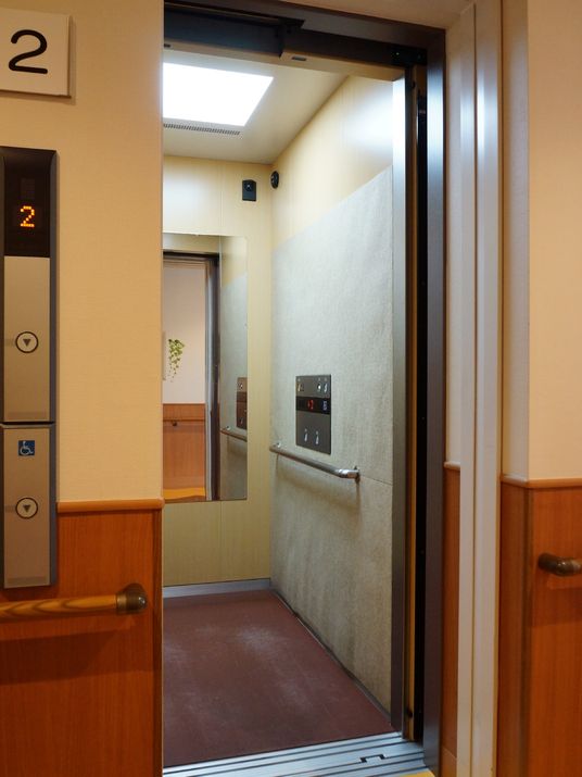 エレベーターホールには手すりがある。ボタンは車いす用も付けられている。エレベーター内は明るく、中にも手すりがある。