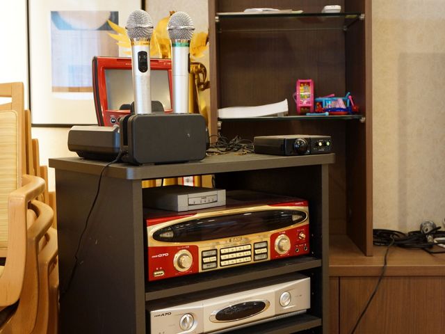 カラオケ機器のある棚 カラオケ 日々のレクリエーションに役立つカラオケ設備が整っており、楽しいひと時を過ごせる空間です。