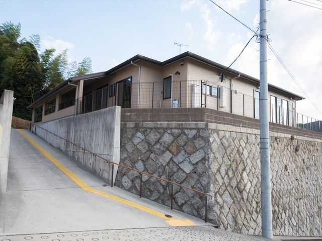 施設の外観が見える風景 外観 斜面に位置する建物は自然に囲まれ、バリアフリー設計のため車椅子でも安心して移動できるよう配慮されています。