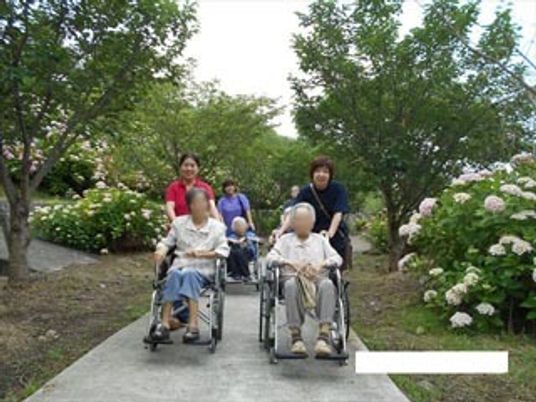 車椅子で散歩する人々とスタッフ