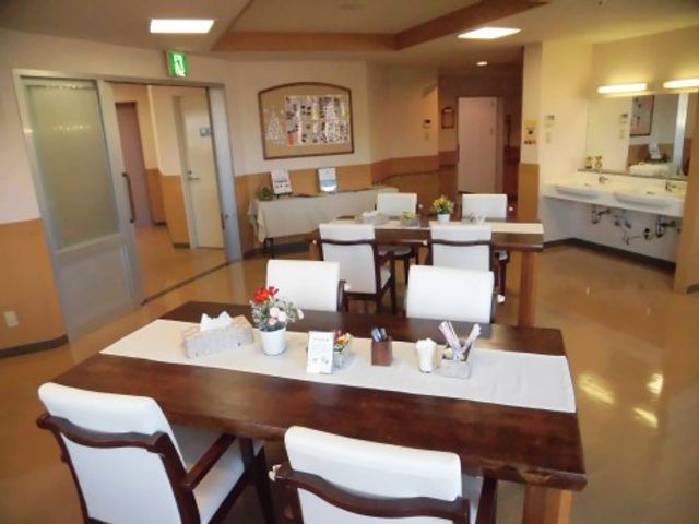ダイニングの居心地の良い空間 リビング ゆったりとしたダイニングでは、花が飾られたテーブルで食事が楽しめ、キッチンカウンターも見えます。安心して働ける温かみのある環境です。