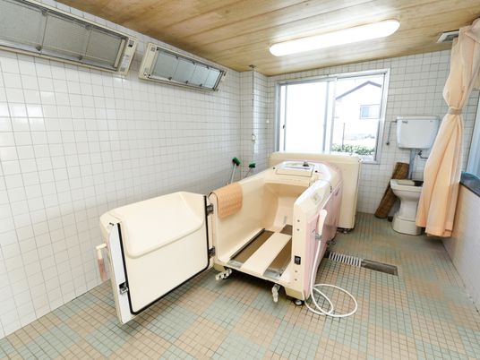 座ったままの姿勢で入浴するための介護入浴機器が設置されている。また、浴室の天井は木材で作られているためあたたかみのある印象である。