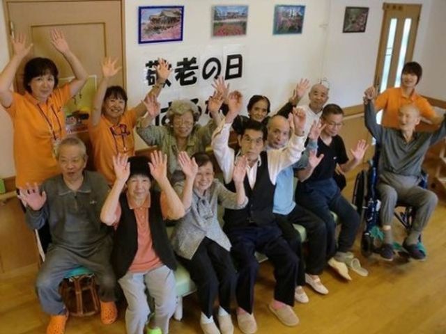 活気ある活動の様子 イベント スタッフと利用者が一緒に腕を挙げて笑顔でポーズをとっており、和やかで元気な雰囲気が伝わってきます。これは明るい印象の職場であり、たくさんの笑顔があふれる場所でのお仕事をご検討いただけることでしょう。