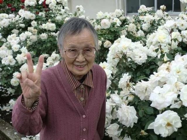 笑顔のおばあさんと花 イベント 庭園で楽しそうに笑顔を見せる利用者の姿。植物に囲まれながら、穏やかな時間を過ごしていただけます。