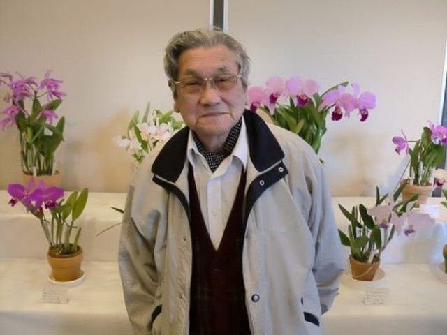 花と共に立つ笑顔のおじいさん イベント カラフルな花々に囲まれ、優しい笑顔を見せる利用者の様子です。生活の中で自然と触れ合える環境が整っています。