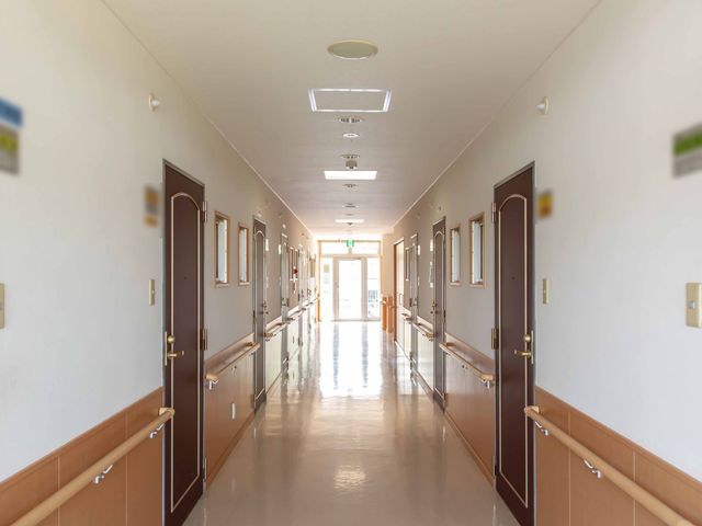 明るい廊下と部屋の扉 廊下 清潔感のある広々とした廊下が、快適な勤務環境を提供しています。壁には明るくゆったりした雰囲気が感じられます。