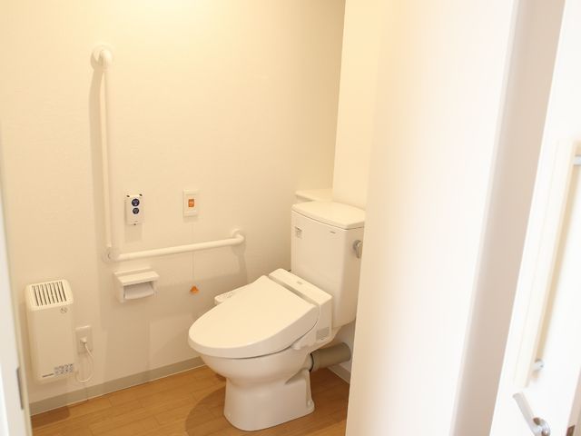 手すり付きのトイレ空間 居室のトイレ 手すりが備わり、床も滑りにくい仕様になっており、利用者の方々の自立を支える環境が整っています。安全かつ快適にご利用いただけます。