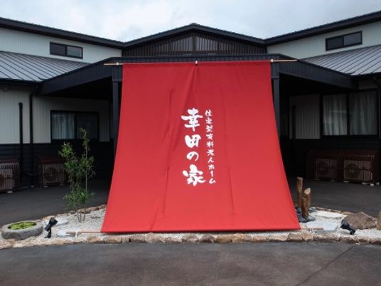 高級旅館のような外観の木造平屋建て。大きな赤い布に書かれた屋号が目印になっている。全28室の比較的小規模な施設である。