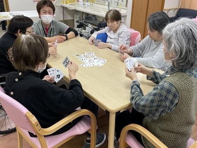 共有スペースでのカードゲーム 多目的室 温かみのある多目的室で、ご入居者がカードゲームを楽しんでいます。会話も弾む明るい場です。