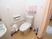 居室に設置された洋式トイレ。壁にはＬ字型の手すりやナースコール、ピンク色のラックが取り付けられている。