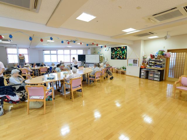 ゆったりした共有スペース 共有スペース 広々とした明るい食堂で、ご利用者が円卓を囲み楽しげに過ごしています。様々な活動ができるスペースが確保され、コミュニケーションも活発です。