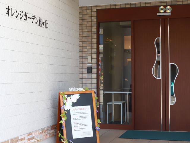 エントランス前の案内板 入り口 お出迎えの案内板が置かれたエントランスです。温かな雰囲気をもった出入り口は、皆様を優しく迎え入れます。
