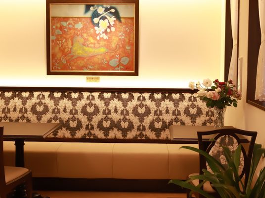 ロビー奥の机や椅子周辺の壁には絵画が飾られ、机の上には花が飾られており、華やかな様子である。くつろぎの空間となっている。