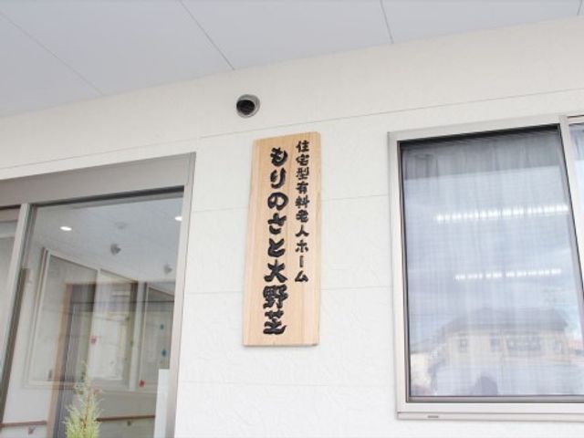 看板を示す外観 施設看板 温かみのある木製看板が目を引くエントランスです。来訪者を優しく迎え入れるデザインが印象的で、快適な環境を感じさせます。
