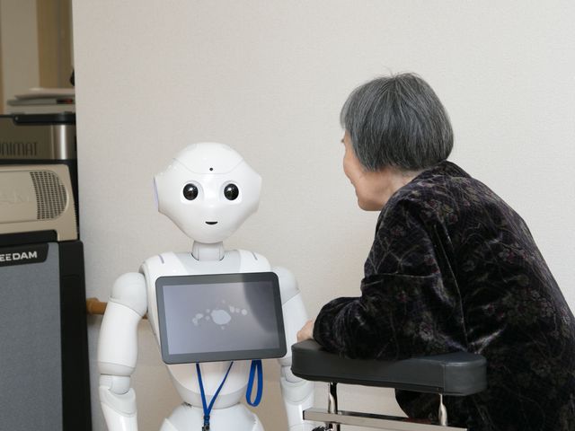 ロボットと話す利用者 ペッパーくんと話す入所者 最新技術を使った支援が行われています。利用者一人ひとりと丁寧なコミュニケーションを取る姿が見られます。