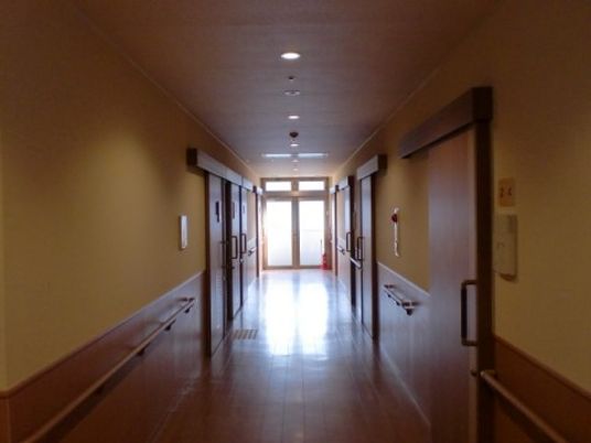 広々としたスペースの廊下である。両側に部屋のドアが並び、全壁に手すりを完備している。正面に大きなガラス戸がある。