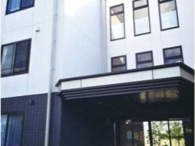 白と黒の外観 玄関 明るい日差しが差し込むモダンな建物です。広々としたエントランスがあり、開放感が感じられます。