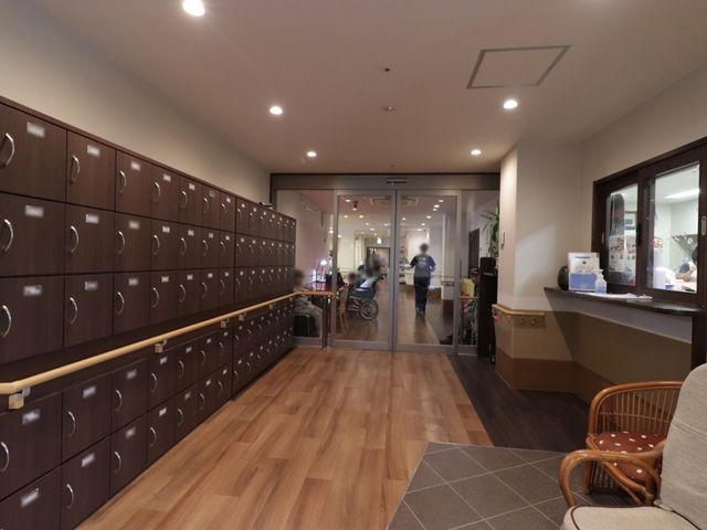 手すり付き廊下の風景 玄関 ゆったりとした通路には安全のための手すりが設けられ、職員が行き交う活気のある空間です。明るく清潔感のあるこの場所は、働く環境としても心地よいでしょう。