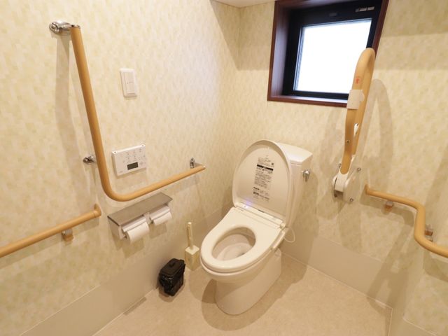 バリアフリー設計のトイレ トイレ 手すりが設置された明るいトイレです。利用者の安全と快適さを考慮した機能的な空間が整っています。