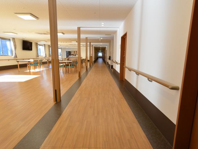廊下と食堂の風景 居室前のキッチン、食堂スペース 手すり付きの廊下が続く、清潔感のあふれる食堂です。明るく、ゆったりとした食事の時間をサポートいたします。