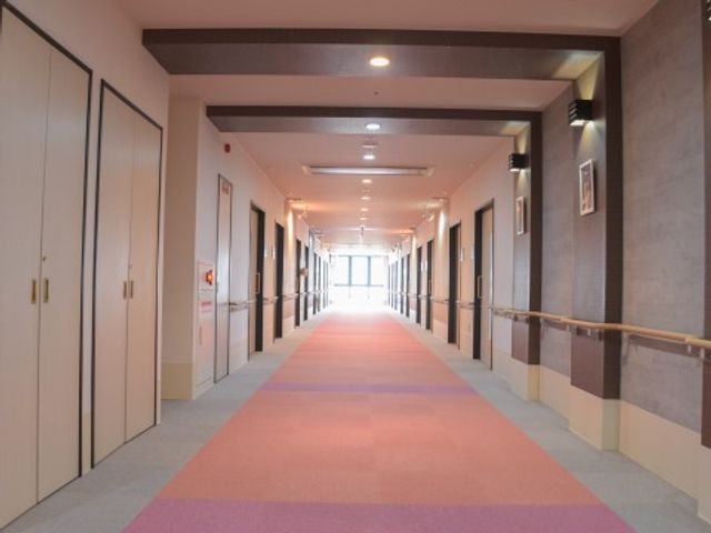広々とした明るい廊下 廊下 手すり沿いに延びるこの廊下は、歩行の補助はもちろん、安全に移動できるようデザインされています。フローリングの色の変わり目が視覚的なガイドとしても機能します。