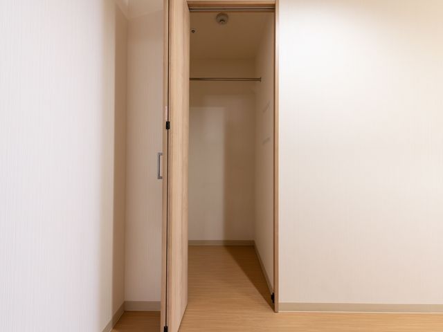 居室の開いた扉 クローゼット 清潔感のあふれる居室の入り口です。ゆったりとした通路が、落ち着きのある生活空間へと導いています。