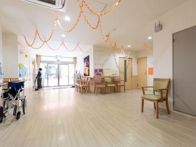 ロビーに立つ人 玄関ホール 広々としたロビーでは、居心地が良さそうに見える人が窓際で穏やかな光を楽しんでいます。周りは清潔感のあふれ、お客様も快適に過ごせる空間です。