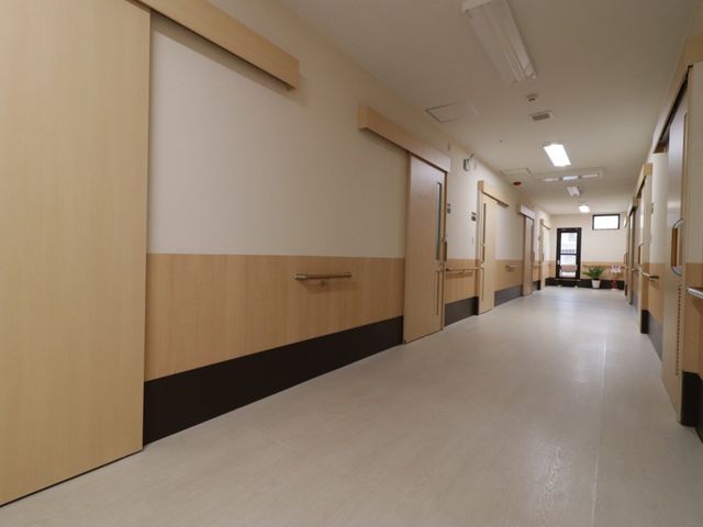 明るく清潔な廊下 通路 広々として清潔感があり、ゆったりと歩ける廊下です。壁面の色合いも落ち着いた雰囲気を醸し出しており、安心してお過ごしいただけます。