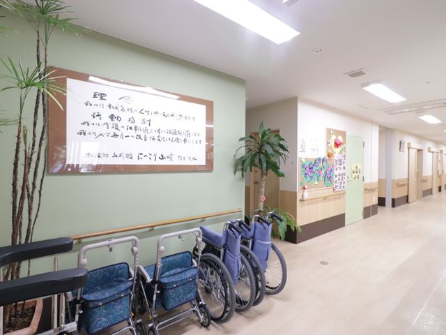 明るい廊下と掲示物 通路 清潔感のある廊下は、車いすを並べたりするためのスペースも確保されており、快適に過ごせる配慮がされています。