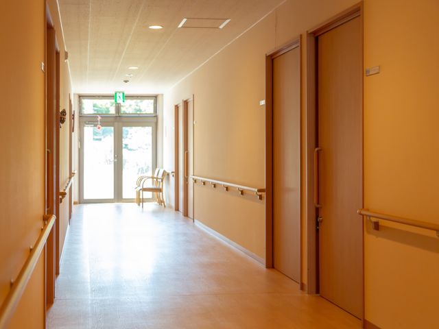 明るい廊下と手すり 通路 広々とした廊下は手すりが整備され、安全な歩行を支援します。日差しが差し込む憩いの場があり、くつろぎの時間を提供しています。