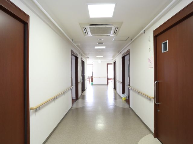 清潔で明るい廊下 廊下 手すりが整った安全な通路です。落ち着いた色合いで、訪れる方々に安心感を与える設計になっています。