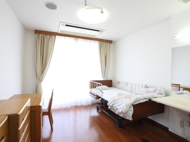 明るい居室の一角 個室 広々とした居室には、日差しが差し込み、ゆったりと時間を過ごせる雰囲気です。必要な家具が整い、快適な生活空間が確保されています。
