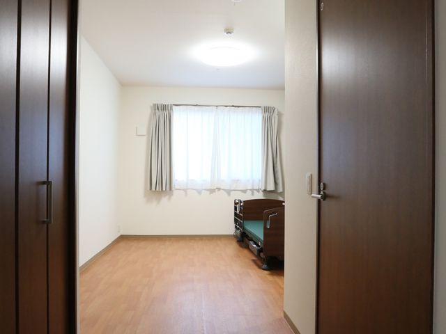 居室の清潔な空間 居室 落ち着いた色合いの居室で、日の光が優しく差し込んでいます。プライバシーを重視した設計が特徴です。