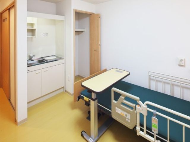 ベッドとキッチンのある居室 居室 清潔感のある居室で、ゆったりとしたベッドと小さなキッチンが備わっており、くつろぎながら自由に生活を送れます。